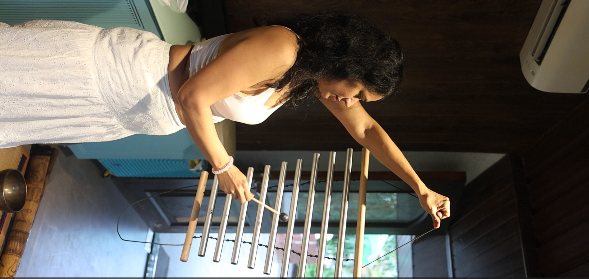 Practitioner leading a sound healing session with tubular chimes